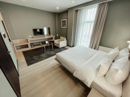 a bedroom with a white bed and a desk at Resident City Hotel in Almaty