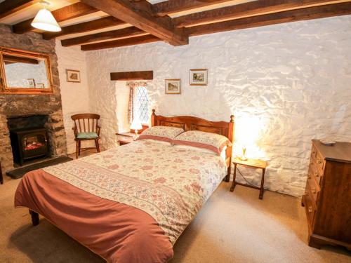 a bedroom with a bed and a stone wall at Nant Cottage in Llanrwst