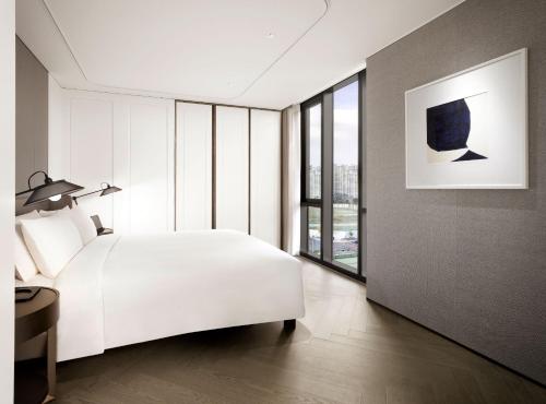 a bedroom with a white bed and a large window at Sofitel Ambassador Seoul Hotel & Serviced Residences in Seoul