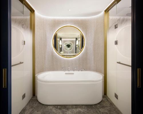 a bathroom with a white tub and a mirror at Sofitel Ambassador Seoul Hotel & Serviced Residences in Seoul