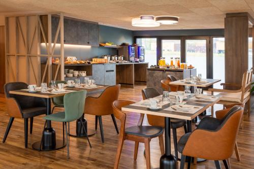 a restaurant with tables and chairs and a kitchen at Best Western Plus Le Conquerant Rouen Nord in Bois-Guillaume