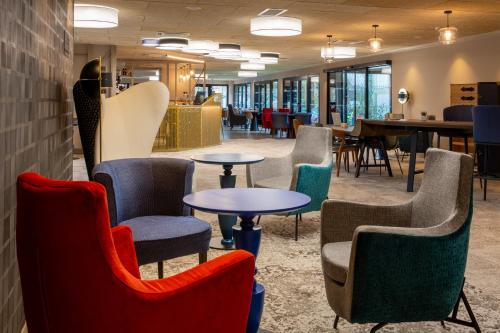a waiting room with colorful chairs and tables at Best Western Plus Le Conquerant Rouen Nord in Bois-Guillaume