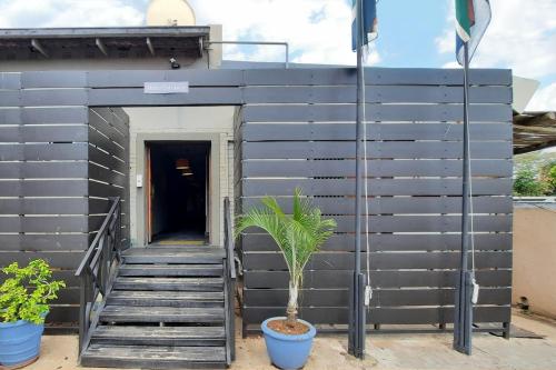 a black building with stairs and a plant in a pot at Elephant Springs in Bela-Bela