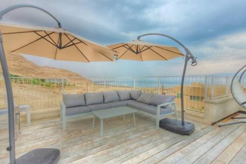 a couch and an umbrella on a deck at Dead Sea Rooftop - גג ים המלח in Ovnat