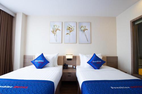 two beds in a hotel room with blue pillows at Sunshine Hotel Móng Cái in Móng Cái