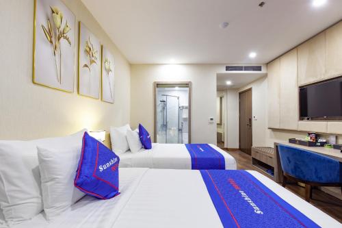 a hotel room with two beds and a flat screen tv at Sunshine Hotel Móng Cái in Móng Cái