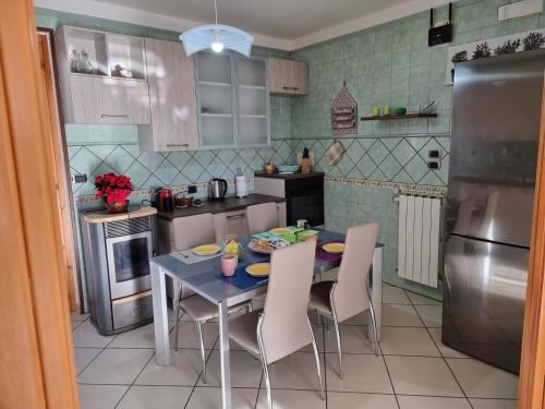 La cuisine est équipée d'une table, de chaises et d'un réfrigérateur. dans l'établissement NickyHouse Holiday Home, à Giffoni Sei Casali