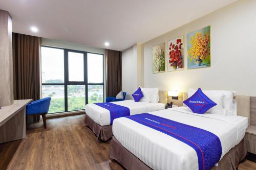 a hotel room with two beds and a window at Sunshine Hotel Móng Cái in Móng Cái