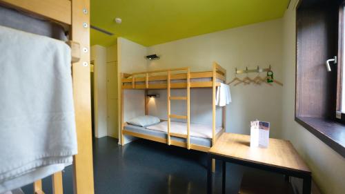 a bunk bed in a room with a table and a bed at Zermatt Youth Hostel in Zermatt