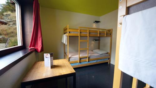 a small room with bunk beds and a table at Zermatt Youth Hostel in Zermatt