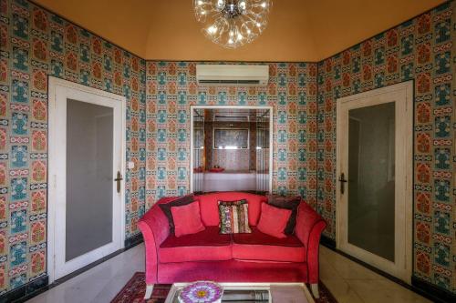 a red couch in a room with wallpaper at Rajmahal Palace RAAS in Jaipur
