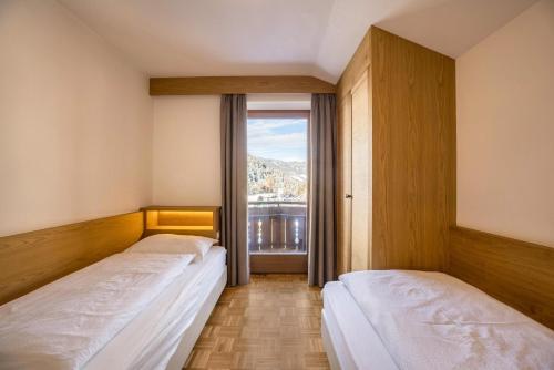 two beds in a room with a window at Rosalpina Apt 4 in San Vigilio Di Marebbe