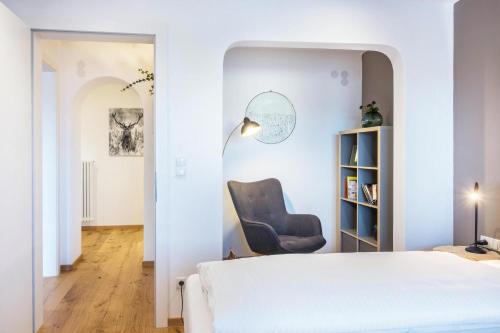 1 dormitorio con silla junto a la cama en Beckenbinder Apartement Rosengarten en San Genesio Atesino