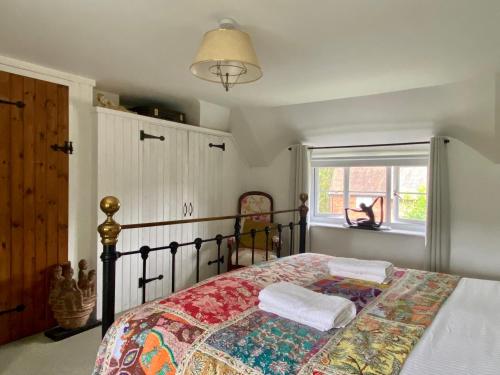 a bedroom with a bed with a comforter and a window at Kings Cottage - Heart of the Deverills in Warminster