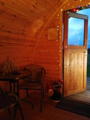 a wooden cabin with a door and a table and chairs at Sunny Mount Glamping Pod in Long Marton
