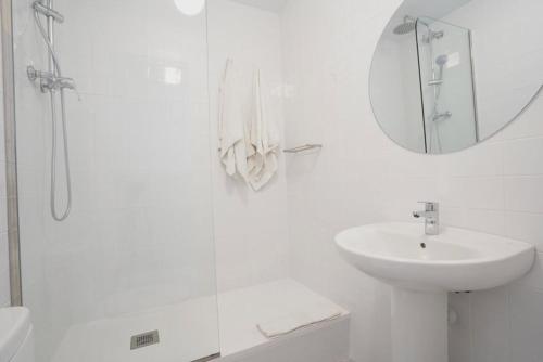 Baño blanco con lavabo y espejo en Hostal Hera en Barcelona