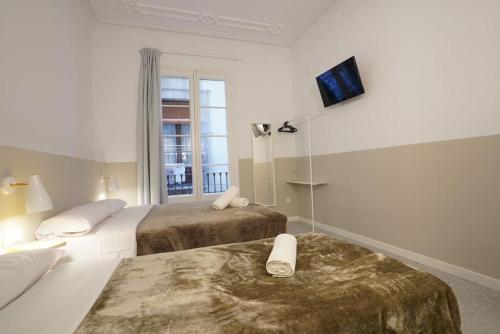 a hotel room with two beds and a tv on the wall at Hostal Hera in Barcelona