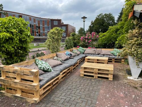 a long wooden couch with pillows on a patio at 't Lytse Knipke in Lemmer