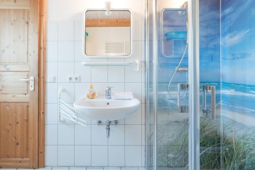 ein Bad mit einem Waschbecken und einer Glasdusche in der Unterkunft Lütt Huus an de Geestkant in Langenhorn