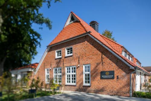 a brick building with a red roof at Weberhof Ferienapartments in Rostrup am Westufer des Zwischenahner Meers in Bad Zwischenahn