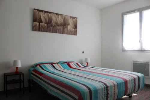 uma cama num quarto branco com um cobertor listrado em Maison de 2 chambres avec jardin clos et wifi a Marsillargues em Marsillargues