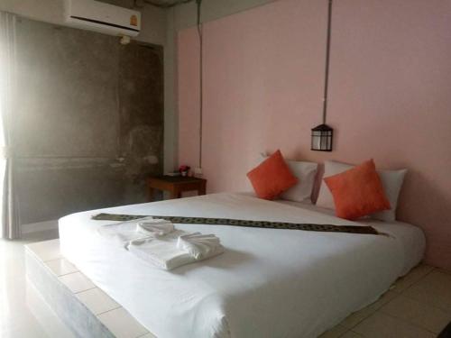喀比的住宿－The Guest Hotel Krabi，卧室配有带橙色枕头的白色床