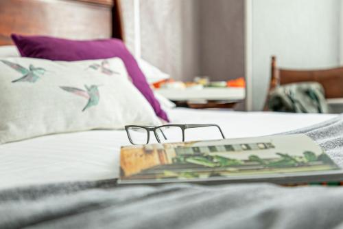 a book and glasses on top of a bed at Southbank TOWN HOUSE in Torquay