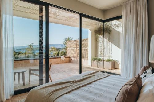 a bedroom with a bed and a large glass window at Maslina Resort in Stari Grad