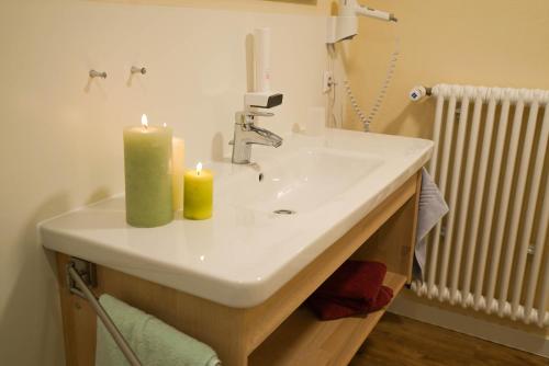 Appartementhotel Breitmattstub في بوليرتال: حمام مع حوض مع وجود شمعتين عليه