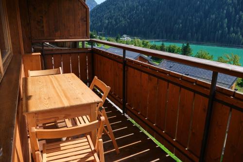 een tafel en stoelen op een balkon met uitzicht op een meer bij Mansarda vista lago in Auronzo di Cadore