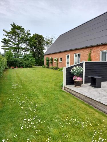 a backyard with a wooden deck and a building at KLAUSIEVEJ B&B in Ulfborg