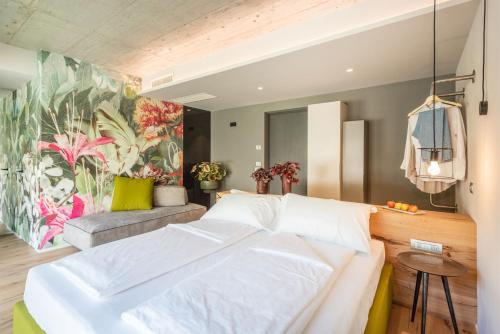 a bedroom with a large white bed and a colorful mural at OLEEVA Garda Living - Adults Only in Riva del Garda