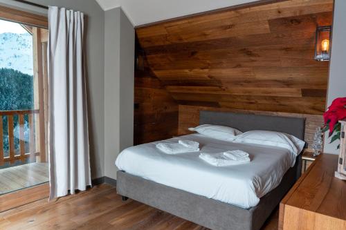 a bedroom with a bed with a wooden wall at Chalet Everest - Luxury Apartments in Prato Nevoso