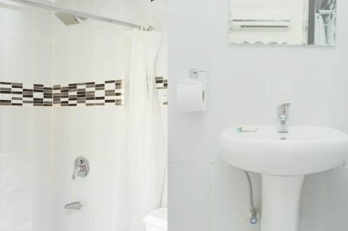 y baño blanco con lavabo y ducha. en Mariners Suites Lagos, en Lagos