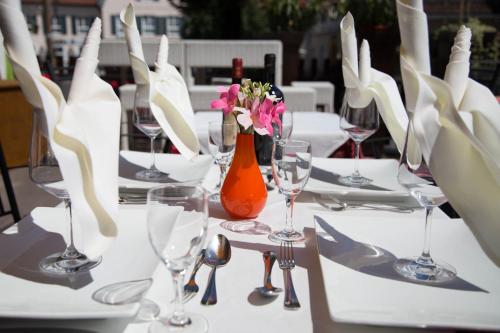 einen Tisch mit Weingläsern und Blumen in einer Vase in der Unterkunft Hotel Ristorante Milano in Bad Tölz