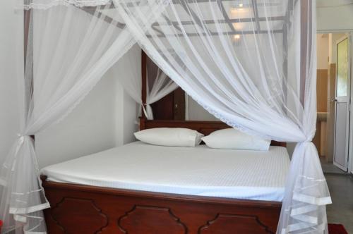a bed with a canopy with white curtains at The Ocean in Galle