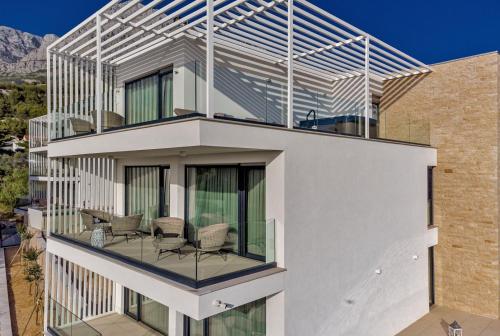 a house with a balcony with chairs on it at Luxury Villa Delight II Promajna with pool, gym, sauna and jacuzzi in Promajna