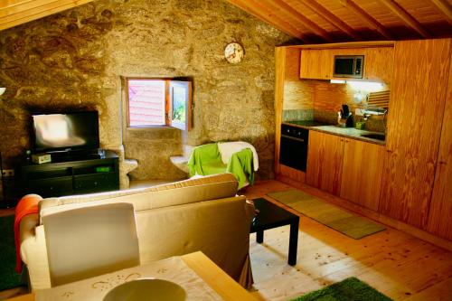 a living room with a couch and a kitchen at Casa do Castanheiro - Eido do Pomar in Arcos de Valdevez