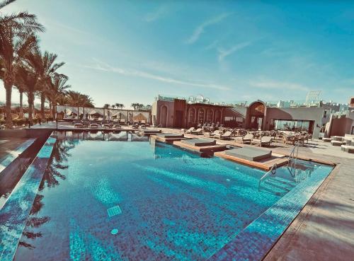 Sunrise Tucana Resort Grand Select- في الغردقة: مسبح كبير مع كراسي صالة ومنتجع