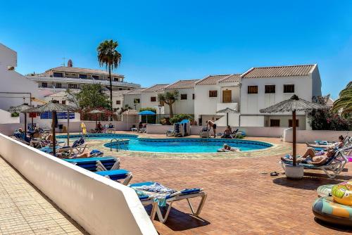 a swimming pool with chairs and people in a resort at Garden City in Playa Fañabe
