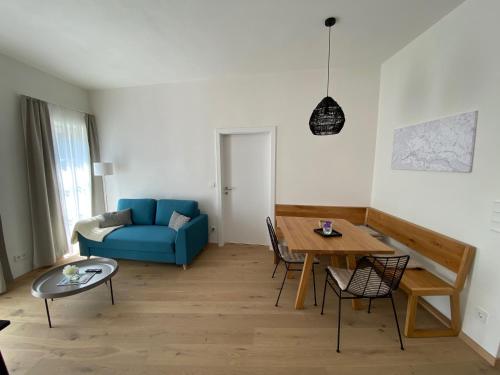 ein Wohnzimmer mit einem blauen Sofa und einem Tisch in der Unterkunft Ferienwohnung Weingut Höllerer in Engabrunn