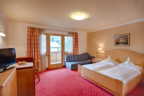 ティローロにあるHotel Eichenhofのベッドとソファ付きのホテルルーム