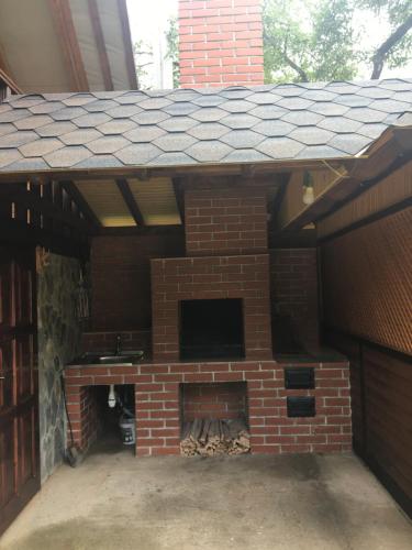 an outdoor brick fireplace with a roof at Шепіт лісу in Sheshory