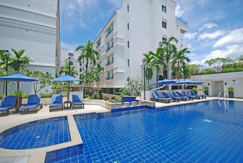 a hotel swimming pool with blue chairs and umbrellas at Tara Angkor Hotel in Siem Reap