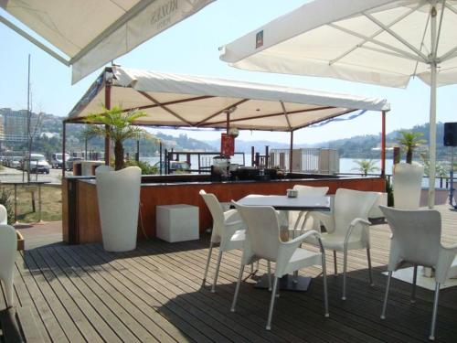 un patio con mesa, sillas blancas y sombrillas en Douro4sailing, en Oporto
