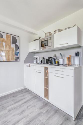 a kitchen with white cabinets and a microwave at Limehome Garching bei München in Garching bei München