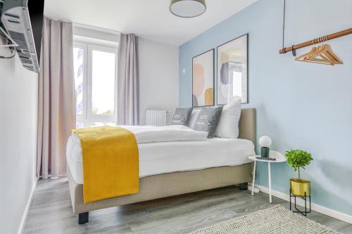 a white bedroom with a large bed with a yellow blanket at Limehome Garching bei München in Garching bei München