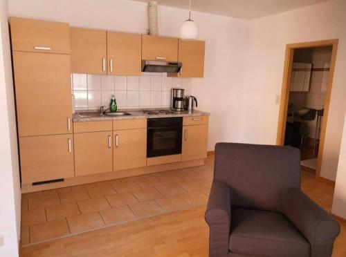 a kitchen with wooden cabinets and a chair in a room at Ferienwohnung in Neustadt-Glewe