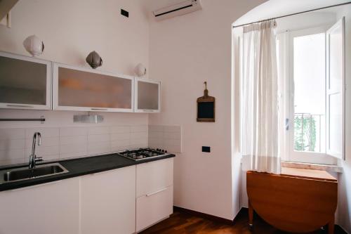 kuchnia z białymi szafkami, umywalką i oknem w obiekcie CASA FISCARDI w mieście Bari