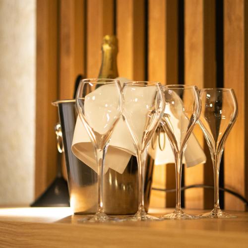 four empty wine glasses sitting on a table with a bottle at Hotel JeštěBrno in Brno